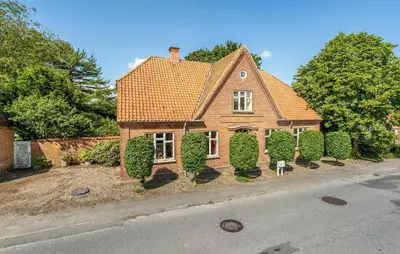 a brick house with bushes in front of a street at 6 Bedroom Amazing Home In Roslev in Roslev