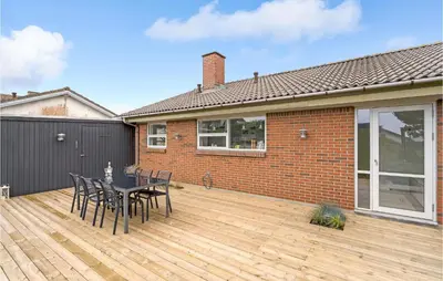 a patio with a table and chairs on a wooden deck at Gorgeous Home In Thisted in Torsted