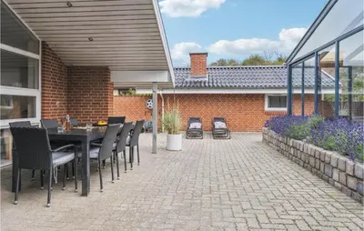 a patio with a table and chairs and a building at Nice Home In Blokhus With Sauna in Blokhus