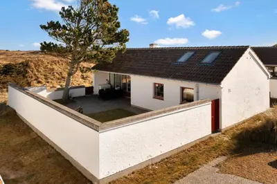 a white house with a concrete wall at Beautiful Home In Pandrup With 2 Bedrooms And Wifi in Pandrup