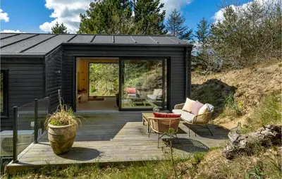 a black tiny house with a wooden deck at 3 Bedroom Cozy Home In Blokhus in Blokhus