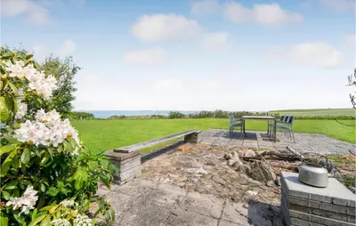 a patio with two chairs and a table in a field at Beach Front Home In Lemvig With Wifi in Lemvig