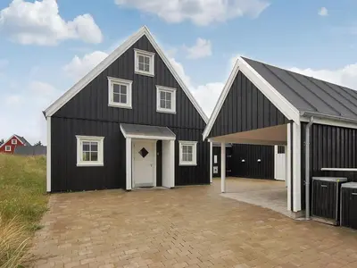 a large black barn with a white garage at Holiday Home Alita - 1-2km from the sea by Interhome in Blokhus