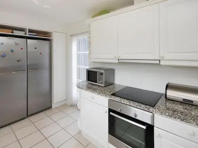 a kitchen with white cabinets and a stainless steel refrigerator at Holiday Home Alita - 1-2km from the sea by Interhome in Blokhus