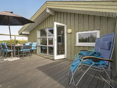 a deck with chairs and a table and an umbrella at Holiday Home Syni - 500m from the sea by Interhome in Pandrup