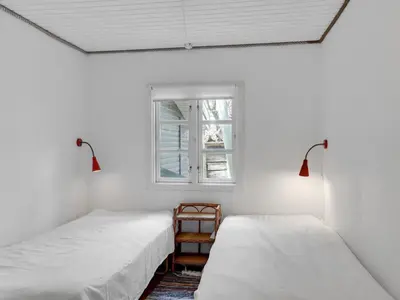 two beds in a white room with a window at Holiday Home Sharanya - 500m from the sea by Interhome in Blokhus