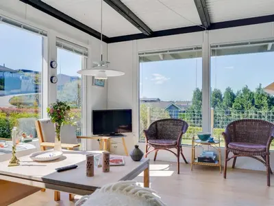 a living room with a table and chairs and large windows at Holiday Home Vasilij - 300m to the fjord by Interhome in Farsø