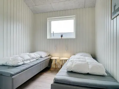 two beds in a room with a window and a table at Holiday Home Grimar - 600m from the sea by Interhome in Torsted