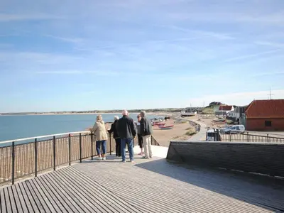 a group of people walking on a boardwalk near the water at Holiday Home Grimar - 600m from the sea by Interhome in Torsted