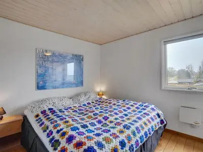 a bedroom with a bed with a colorful comforter and a window at Holiday Home Awer - 300m to the fjord by Interhome in Struer