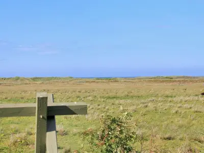 a wooden cross in the middle of a field at Holiday Home Annick - 300m from the sea by Interhome in Fjerritslev