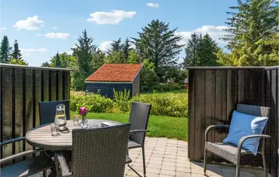 a patio with a table and chairs and a fence at Awesome Apartment In Blokhus With Wifi in Blokhus