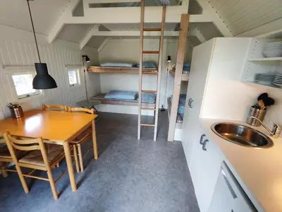 a kitchen and dining room with a table and a bunk bed at Tranum Klit Camping og Hytteudlejning in Brovst