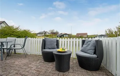 two chairs and a table in front of a fence at 2 Bedroom Cozy Home In Lemvig in Lemvig