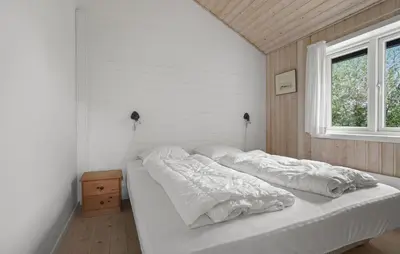 a bedroom with a bed with white sheets and a window at Stunning Home In Vestervig With Sauna in Vestervig
